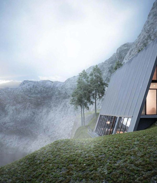 Modern A-frame cabin nestled on a misty mountainside.